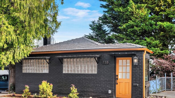 A small black brick house with a wooden door, numbered 718, and a small garden with various plants. - Queen Anne City Escape - 1 bed, 1.5 bath, dog friendly, 1 parking space (Seattle)