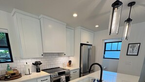 A modern kitchen with white cabinetry, stainless steel appliances, and a central island. - Queen Anne City Escape - 1 bed, 1.5 bath, dog friendly, 1 parking space (Seattle)