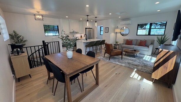 A modern kitchen with white cabinets, a dining area with a wooden table and chairs, a living room with a sofa and a coffee table, and large windows providing natural light. - Queen Anne City Escape - 1 bed, 1.5 bath, dog friendly, 1 parking space (Seattle)