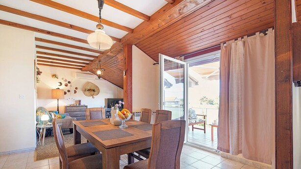 Un espace repas comprenant une table et des chaises en bois, une lampe et une vue sur l’extérieur.