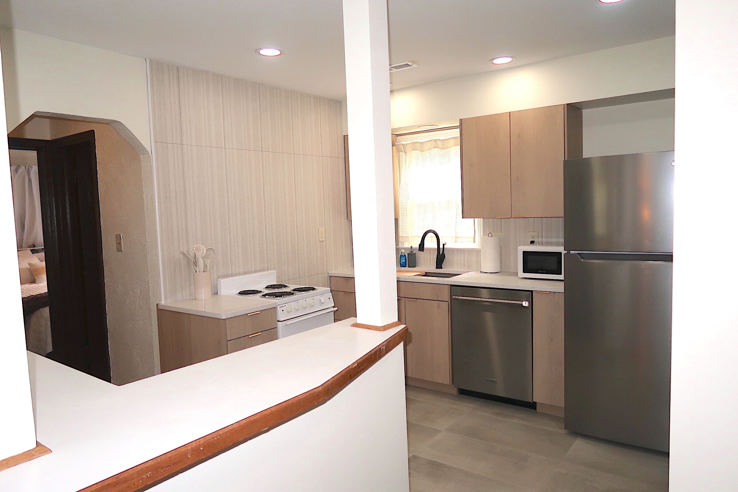 A modern kitchen with stainless steel appliances, wooden cabinets, and a white countertop.