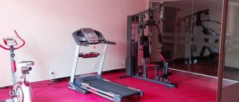Un gimnasio con cinta de correr, bicicleta estática y máquinas de pesas.