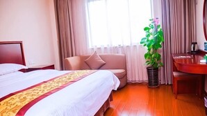 A hotel room with a bed, a sofa, a dining table, and a potted plant. - GreenTree Inn (Shanghai Jiangyue Road Metro Station) (Shanghai)