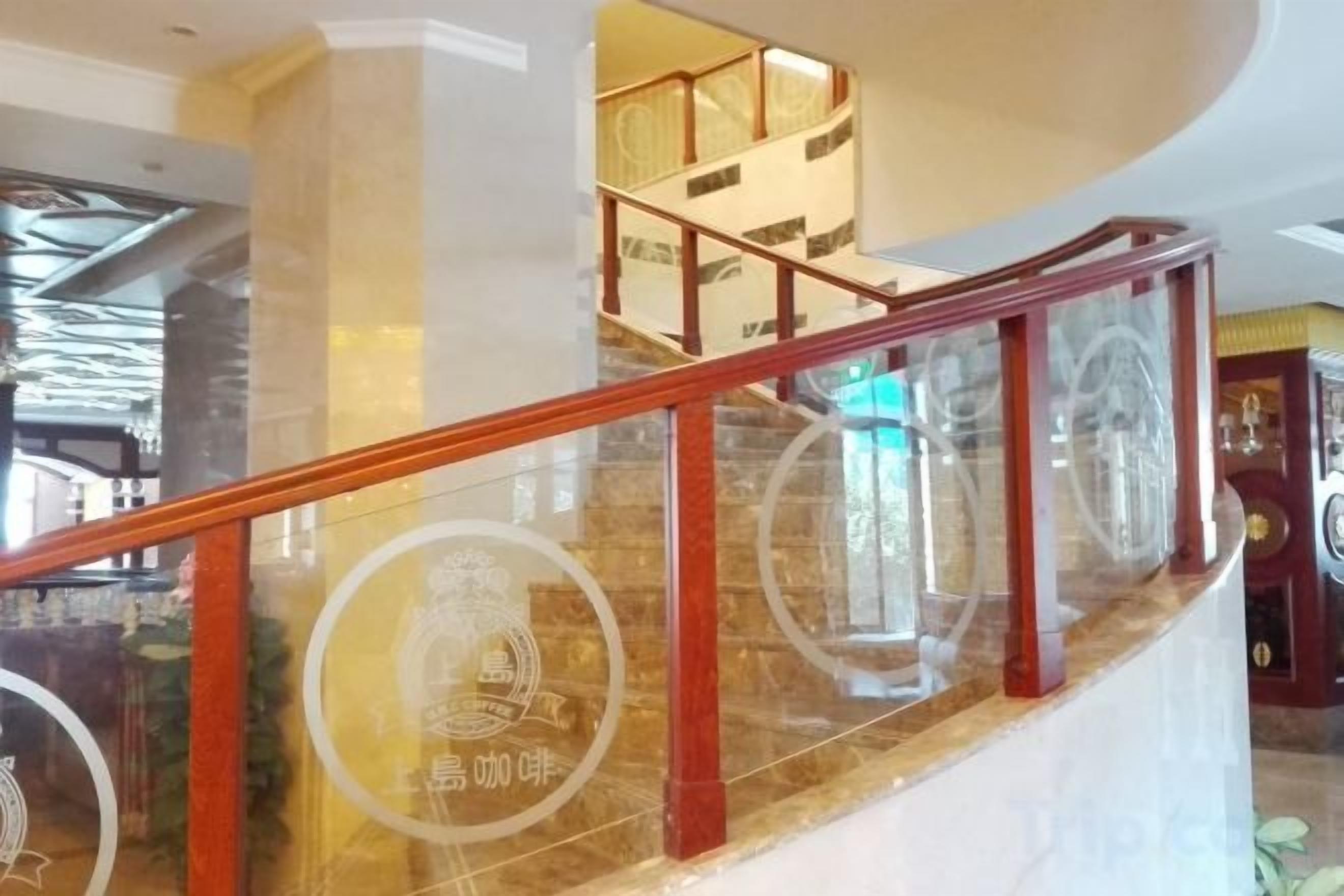 A curved staircase with glass railings and a wooden handrail, leading to an upper level.