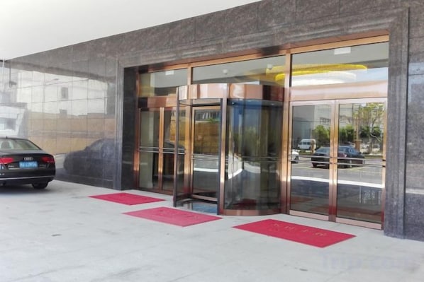A revolving door entrance to a building with a car parked nearby. - GreenTree Inn (Shanghai Jiangyue Road Metro Station) (Shanghai)