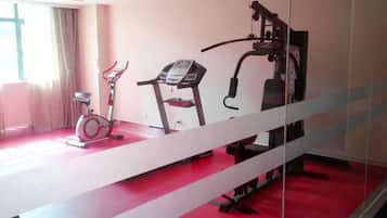 Academia com bicicletas ergométricas, esteira e equipamentos de ginástica.