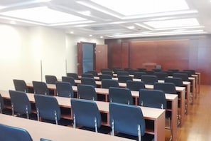 A conference room with rows of tables and chairs, a wooden cabinet, and a large door. - GreenTree Inn (Shanghai Jiangyue Road Metro Station) (Shanghai)