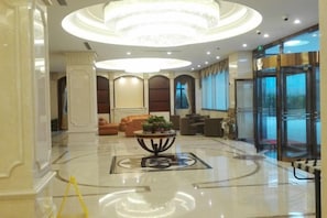 A hotel lobby with a central round table, seating area, and a revolving door. - GreenTree Inn (Shanghai Jiangyue Road Metro Station) (Shanghai)