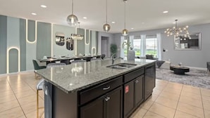A modern kitchen with a central island, pendant lighting, and a view of the outdoors. - FL- 1904 Nice Ct (Kissimmee)