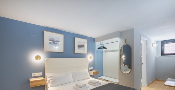 A modern bedroom with a bed, bedside tables, a mirror, and framed pictures on the wall.