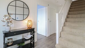 Un intérieur moderne avec une console noire, un miroir rond et un escalier menant à une porte.