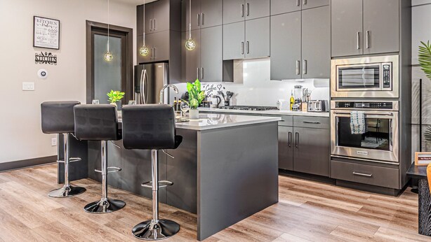 A modern kitchen with dark cabinets, stainless steel appliances, and a central island with bar stools. - [Royal Luxury] Dallas Oak Lawn Lux - 8 bedrooms 7 baths ,2 Gamerooms, 2 Hot Tubs (Dallas)