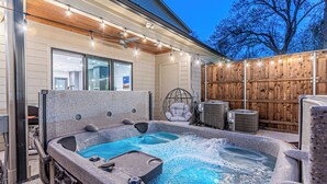 A hot tub with a wooden deck and string lights, a chair, and an air conditioning unit. - [Royal Luxury] Dallas Oak Lawn Lux - 8 bedrooms 7 baths ,2 Gamerooms, 2 Hot Tubs (Dallas)