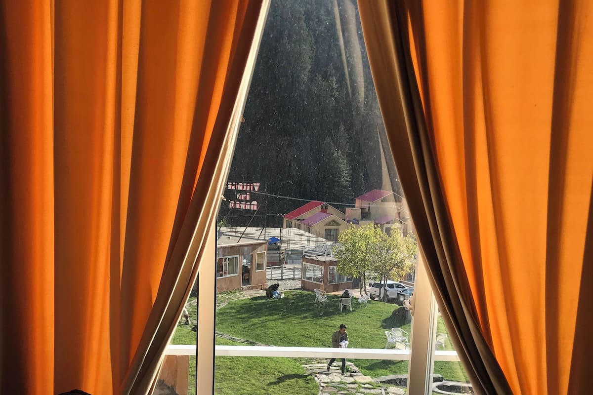 A room with a large window, curtains, and a sofa.
