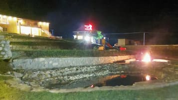 Escena nocturna con un edificio que tiene una escalera y un pequeño estanque.