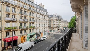 Une vue de rue avec des immeubles à plusieurs étages, un fourgon blanc et un auvent rouge.