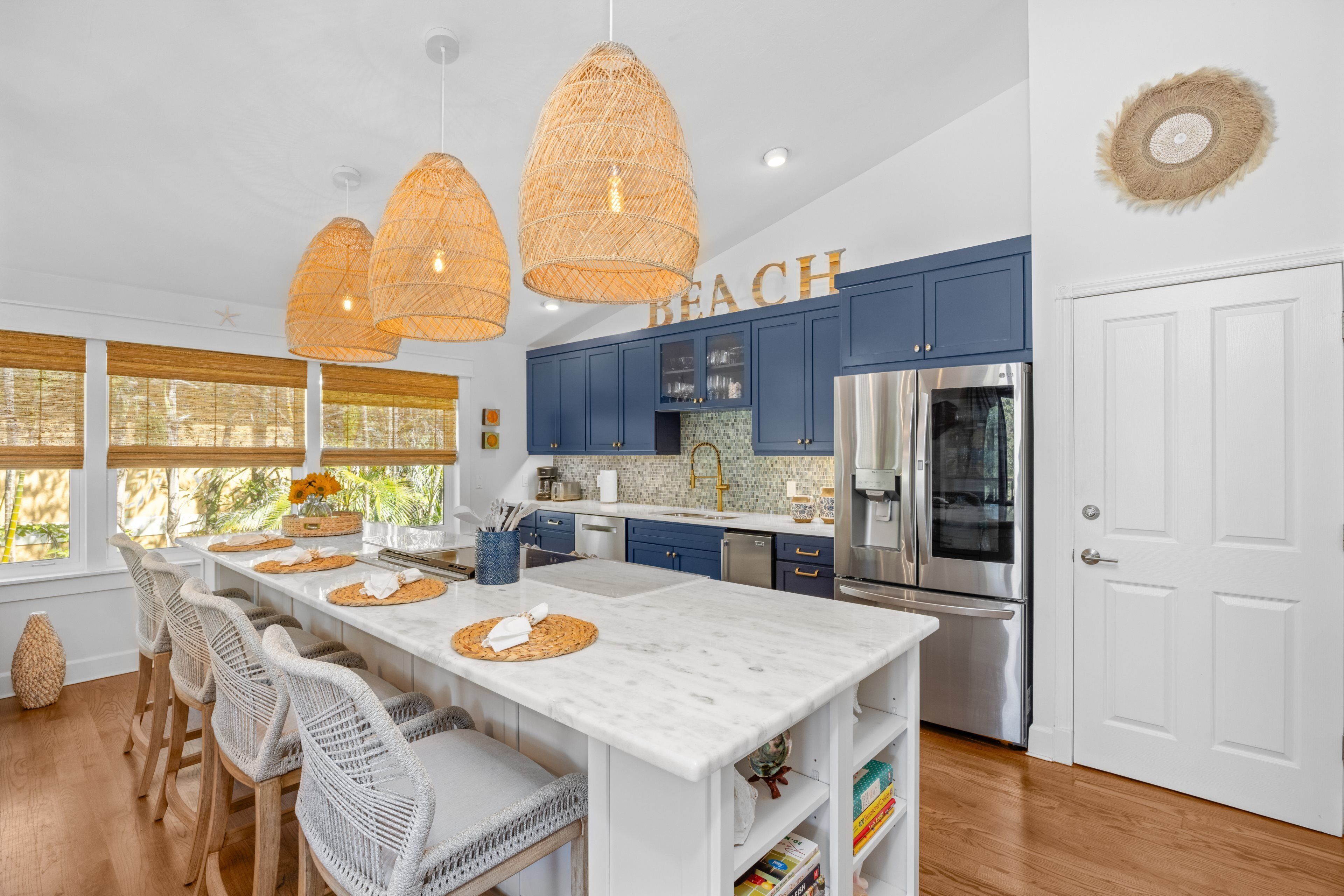 A modern kitchen with white marble countertops, blue cabinets, and a stainless steel refrigerator.
