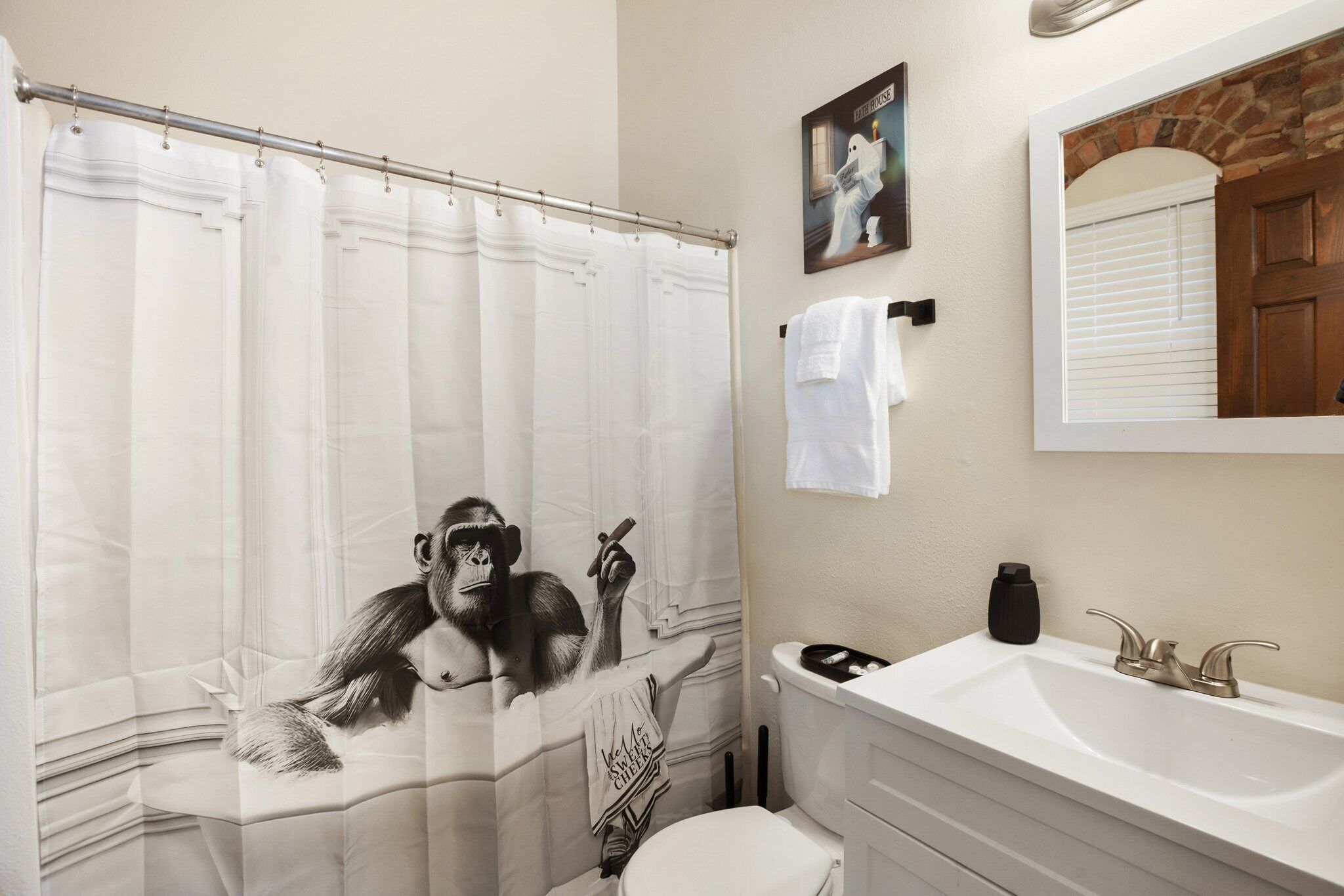 A bathroom with a shower curtain, a toilet, a sink, and a mirror.