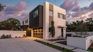 Ein modernes, zweistöckiges Haus mit Garage, Auffahrt und einem gepflegten Garten.