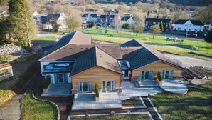 A modern two-story house with a sloped roof, a front porch, and a well-maintained lawn.