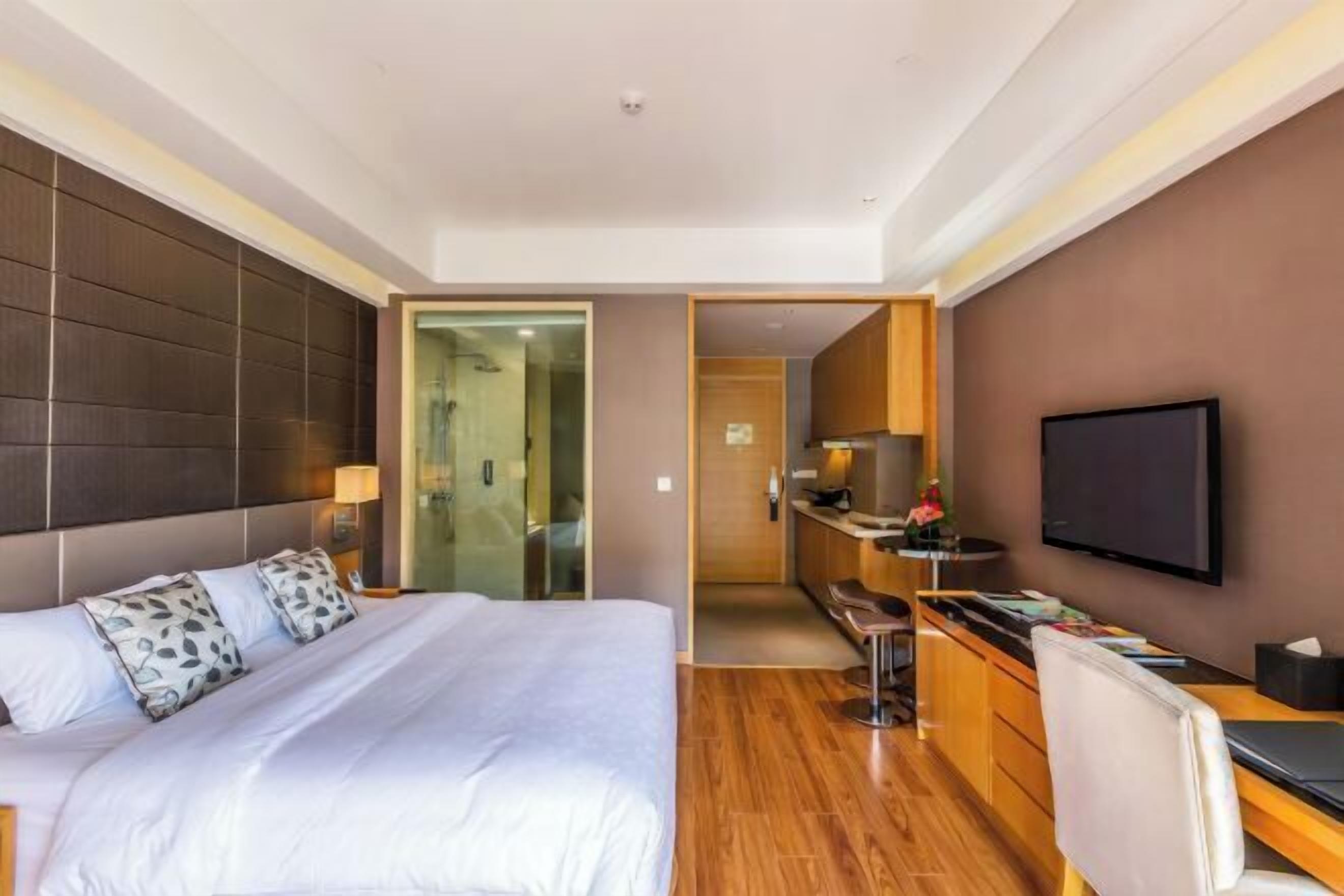 Camera d'albergo con un letto grande, una scrivania, un televisore e un bagno visibile attraverso una porta aperta.