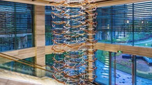 A modern interior with a unique hanging sculpture, large windows, and a glass railing.