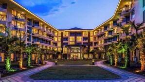 A multi-story hotel with a central courtyard, balconies, and a well-lit entrance.