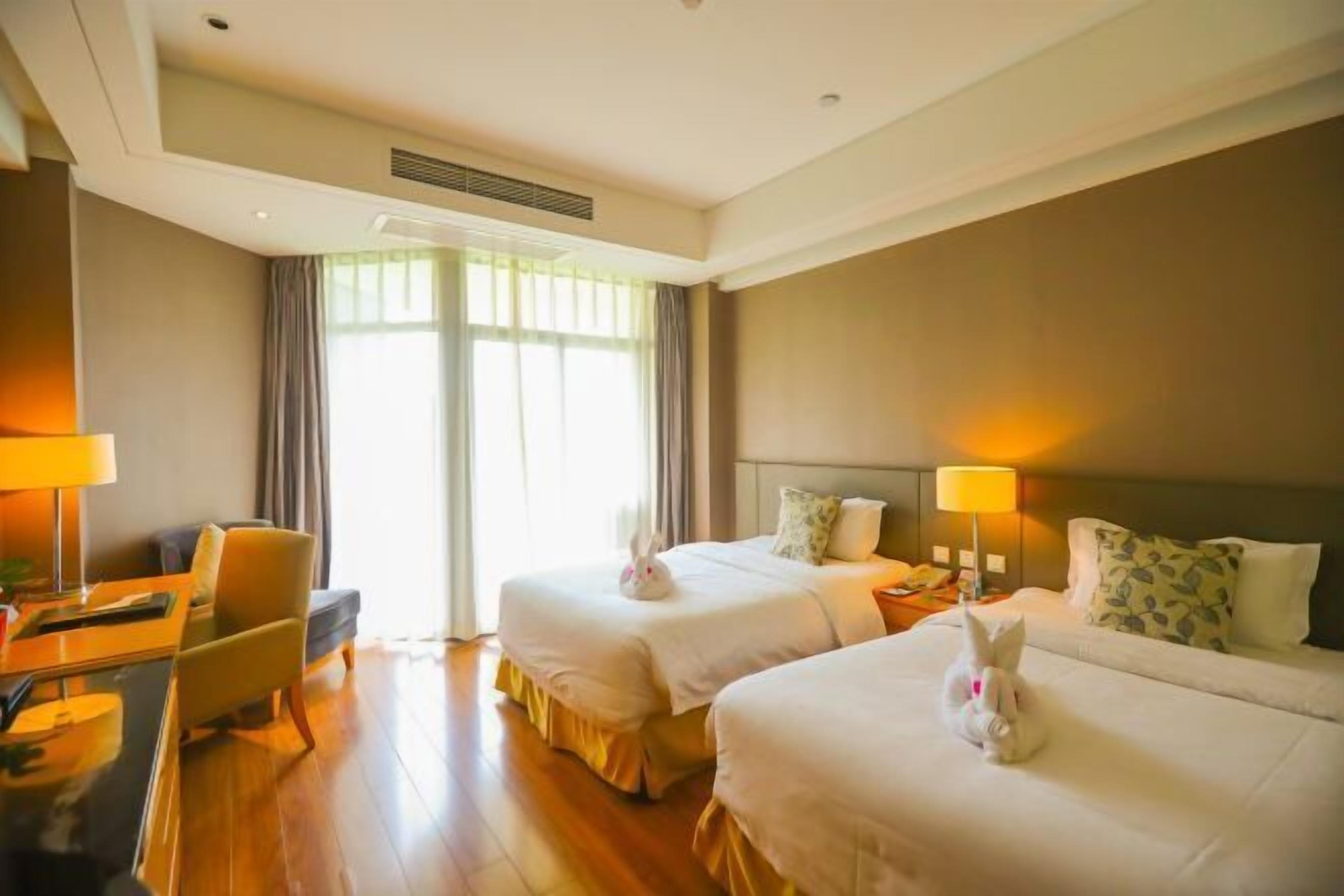 A hotel room with two beds, a desk, and a chair.