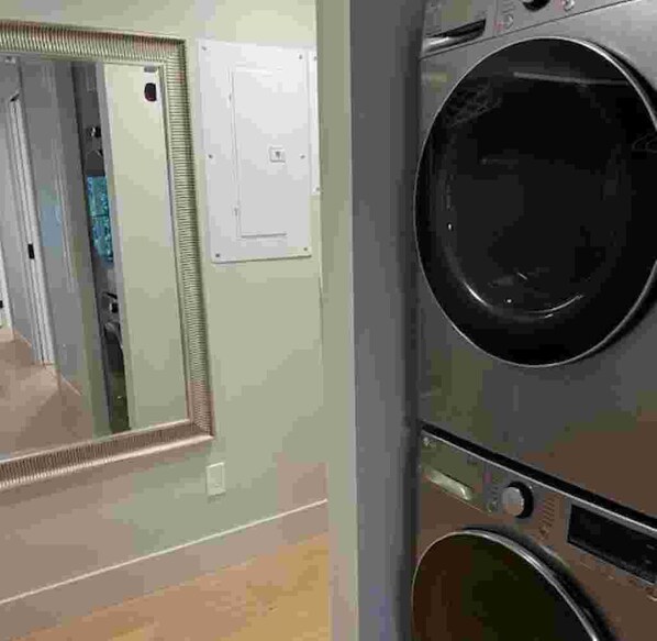A laundry area with a washing machine, a dryer, and a mirror.