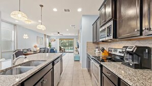 A modern kitchen with granite countertops, stainless steel appliances, and pendant lighting.