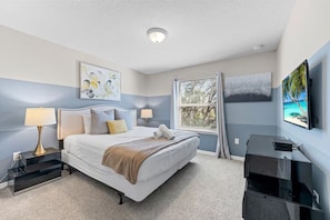 A hotel room with a bed, bedside lamps, a desk with a computer, a window with blinds, and artwork on the walls. - FL- 1905 NICE CT (Kissimmee)