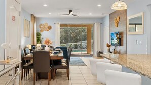 A modern kitchen with a large island, dining area with chairs, and a view of a pool.