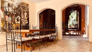 A spacious hall with a tiled floor, a long table with chairs, and a mural on the wall. - Paseo Colonial - Leo's Favorite (Santo Domingo)