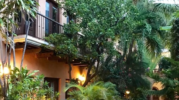 A brick pathway flanked by potted plants and a building with a balcony. - Paseo Colonial - Leo's Favorite (Santo Domingo)