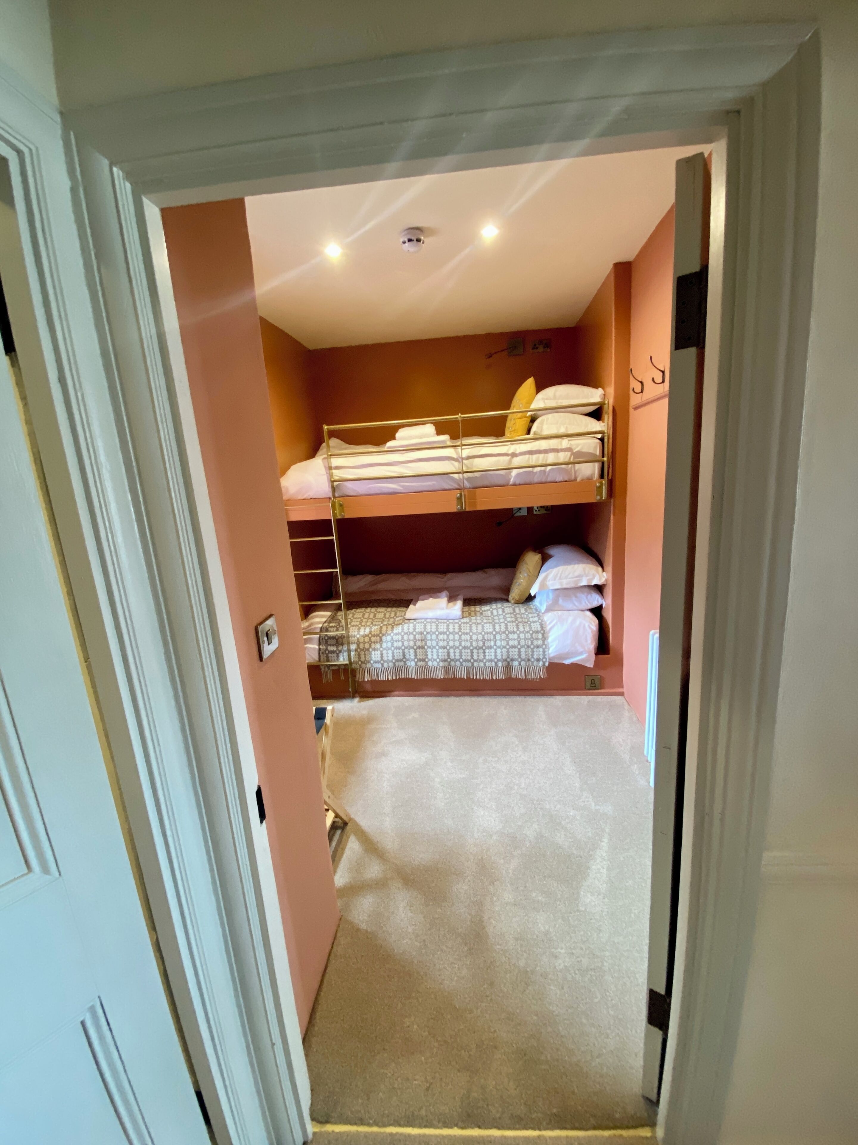 A compact room with bunk beds, a small closet, and a carpeted floor.