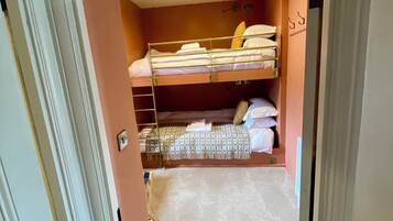 A compact room with bunk beds, a small closet, and a carpeted floor.