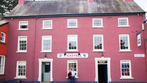 A red building with a sign reading "CASTELL" and a door with a blue awning. - Y Castell  (Llangadog)