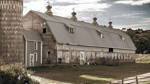 Una grande cascina a un piano con un silo annesso a sinistra.