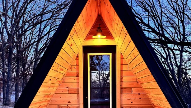 Eine Holzhütte mit einem dreieckigen Dach, einer mittleren Tür und einem kleinen Fenster.