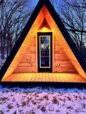 A wooden cabin with a triangular roof, a central door, and a small window. - The A-Frame at Big Rock Creek – A Scenic Retreat on White Oak Ridge (Saint Croix Falls)