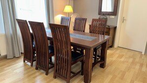 A dining area with a wooden table and chairs, a lamp, and a window with curtains.