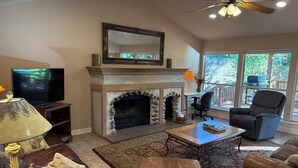 A living room with a fireplace, leather sofas, a television, and a ceiling fan. - Dog-Friendly Lakehouse: Dock + Serene Views (Burnet)