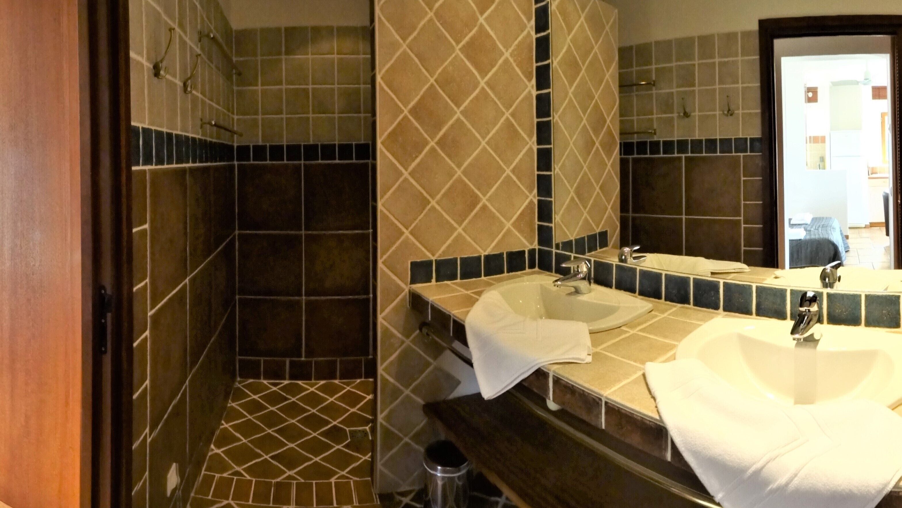 A bathroom with a shower, two sinks, and a mirror.
