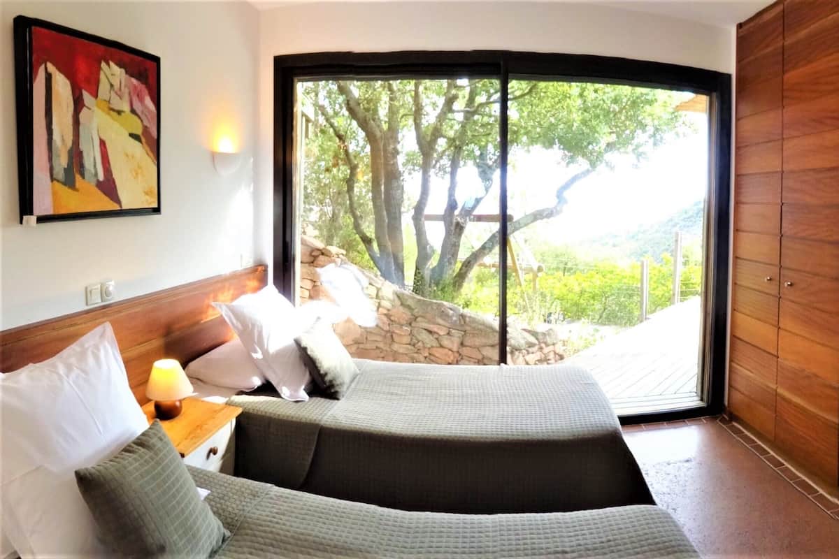Un dormitorio con cama, mesita de noche, lámpara y un cuadro en la pared.