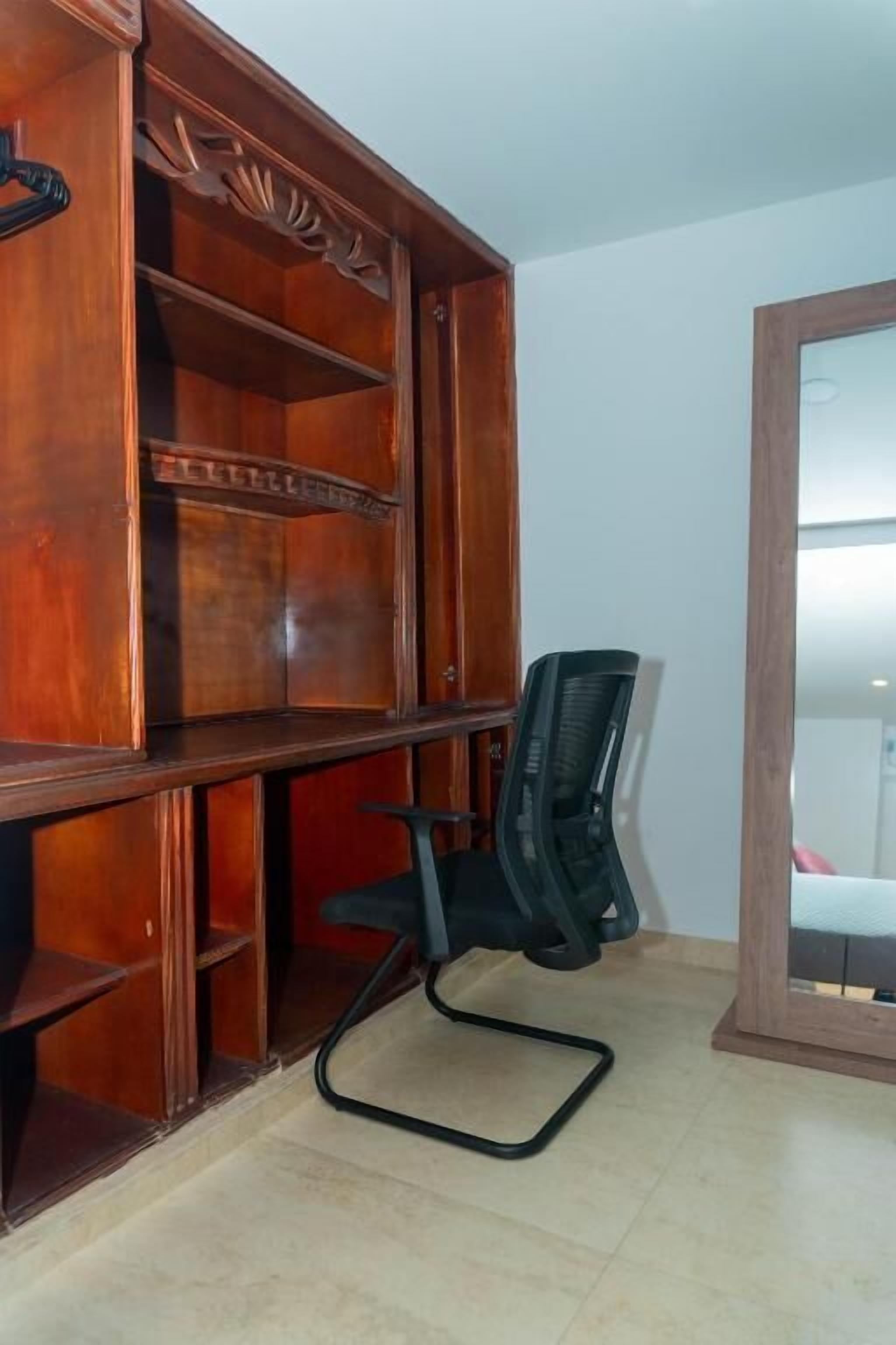 Une étagère en bois avec une chaise de bureau noire placée devant.