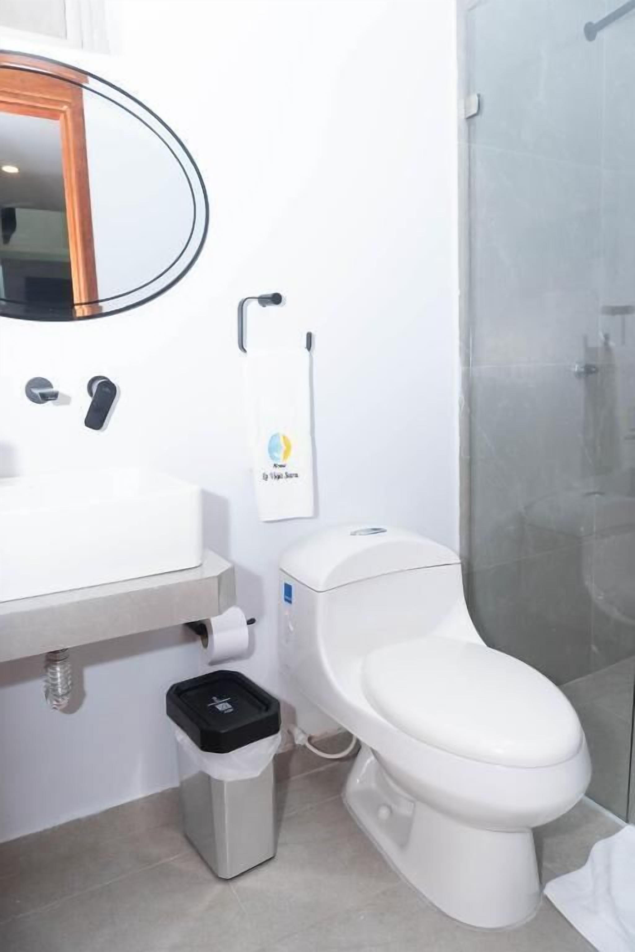 Une salle de bain moderne avec un lavabo blanc, un miroir, des toilettes et une douche.