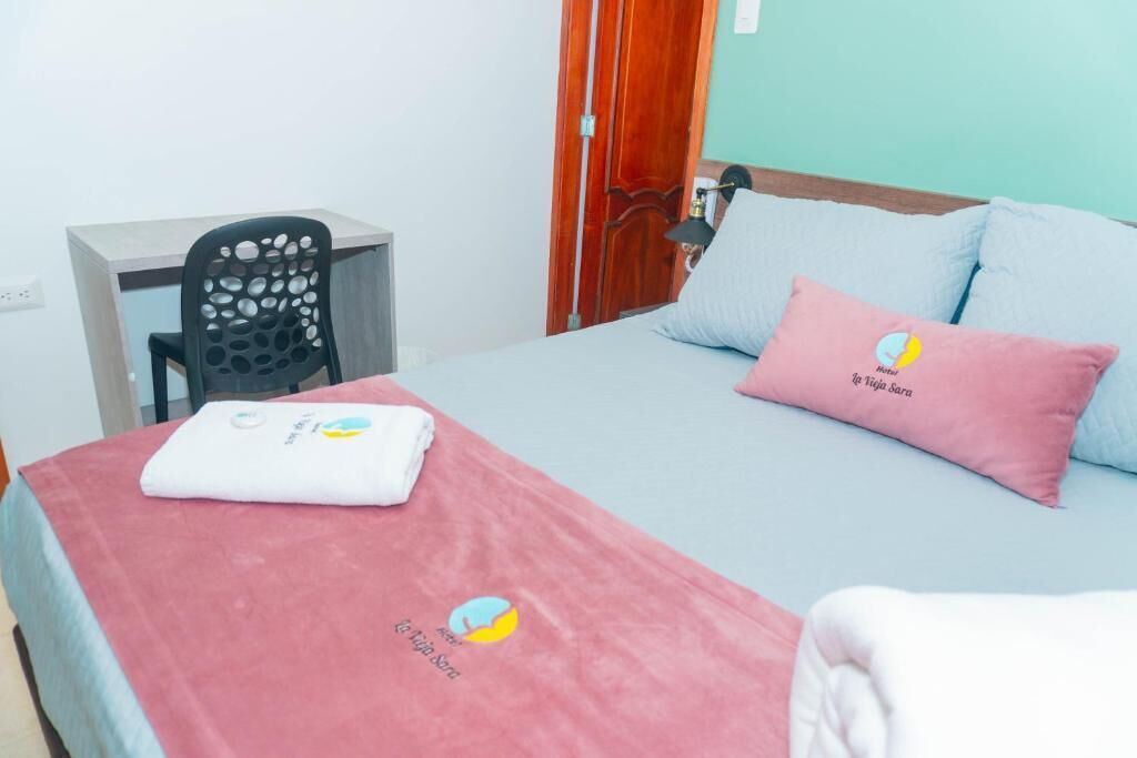 A hotel room with a bed, a desk, and a chair.