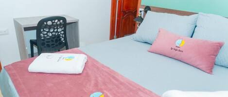 A hotel room with a bed, a desk, and a chair.