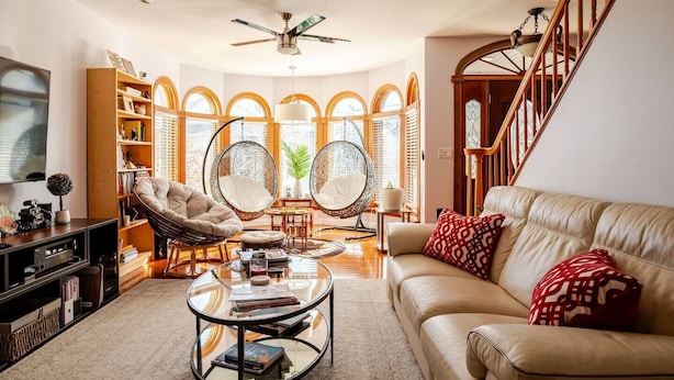 A spacious living room with a leather sofa, round coffee table, and two hanging chairs.