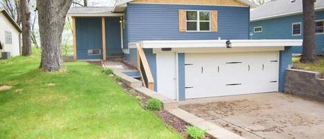 A residential house with a garage, a covered porch, and a well-maintained lawn.